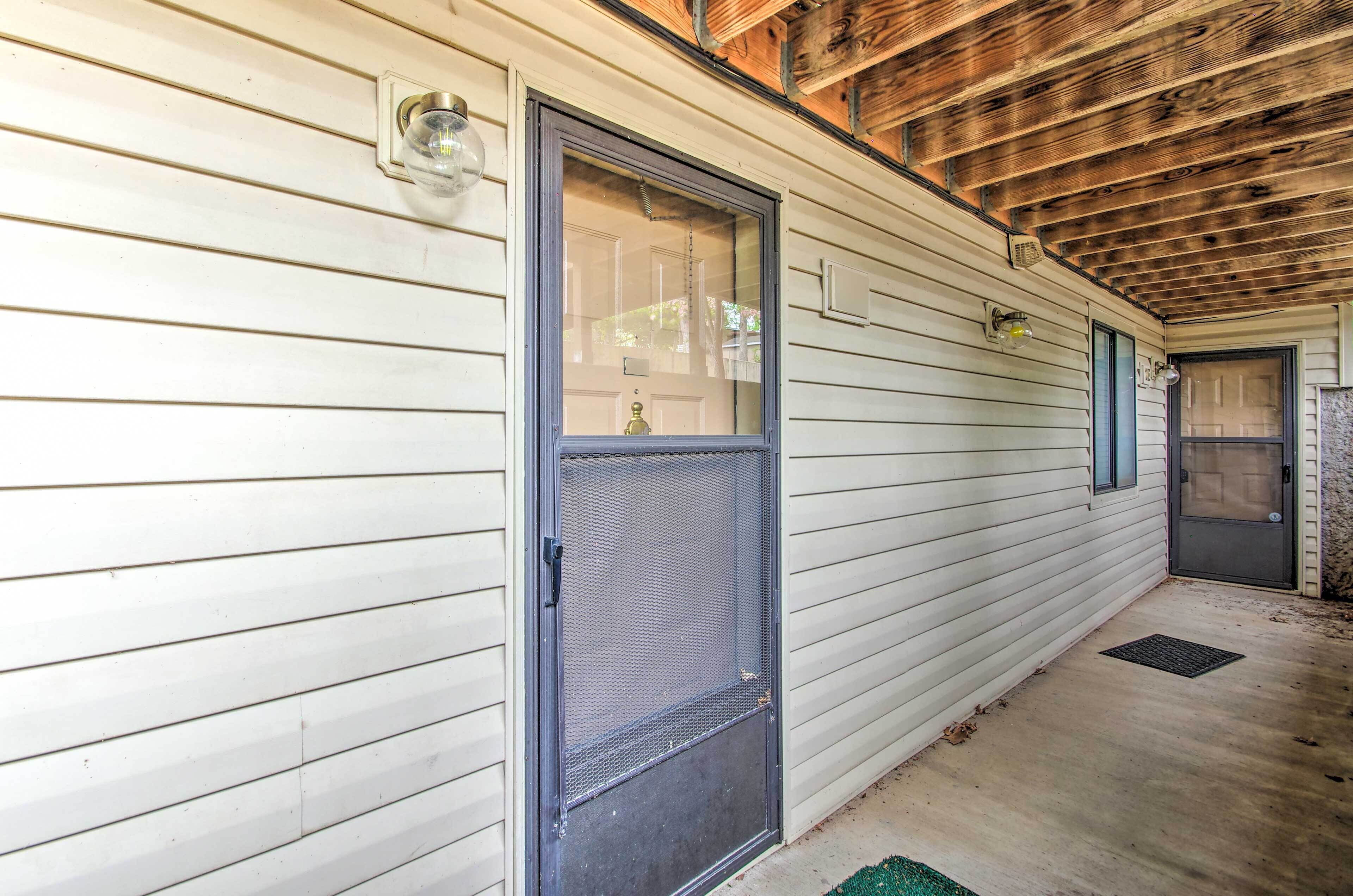A covered porch with a metal door and a small window.
