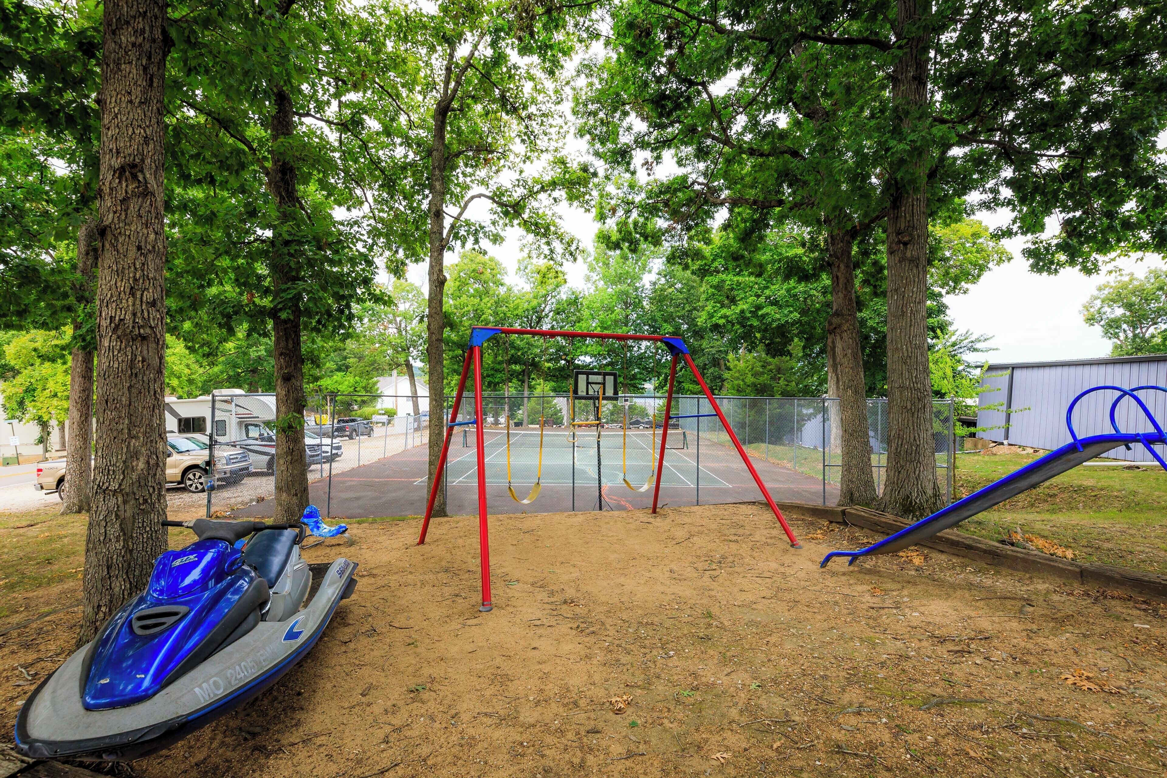 Un'area giochi con altalene, un canestro da basket e un jet ski nelle vicinanze.