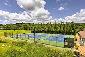 A tennis court with a net, surrounded by a fence, and a building with a chimney in the background. - Ground-floor Condo w/ Hot Tub & Golf Course View (Branson West)
