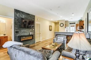 A living room with a fireplace, a television, and a sofa. - Ground-floor Condo w/ Hot Tub & Golf Course View (Branson West)