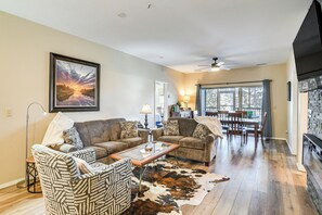 A living room with two sofas, a coffee table, a fireplace, and a dining area with chairs and a table. - Ground-floor Condo w/ Hot Tub & Golf Course View (Branson West)