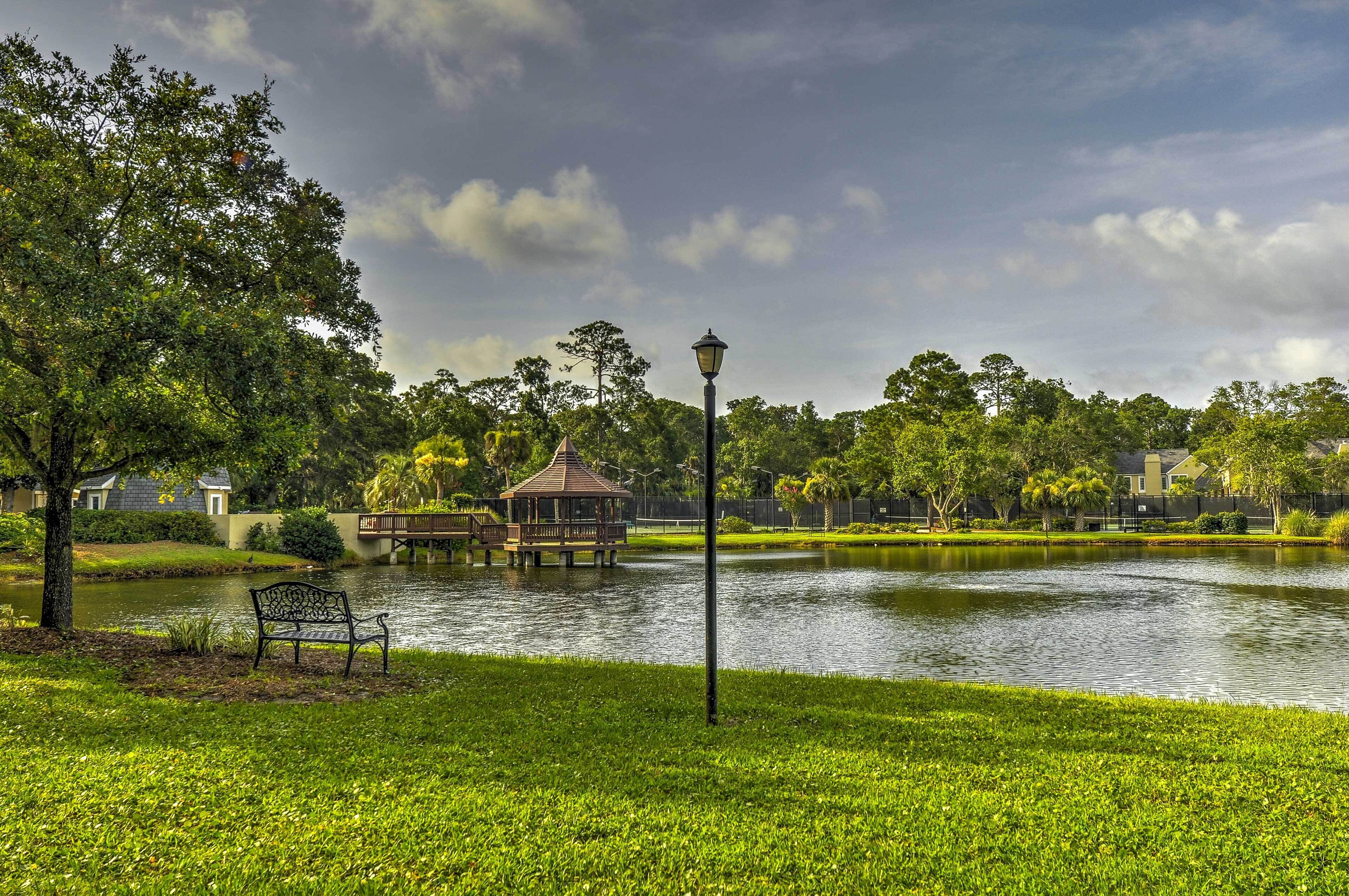 A park with a pond, a gazebo, and a bench.
