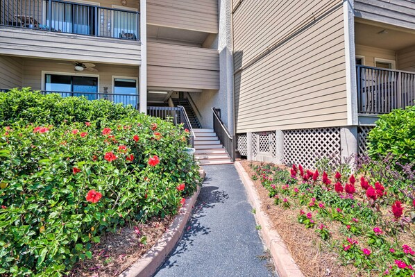 A pathway leading to a building with a balcony and a staircase. - Walk to Folly Field Beach: Condo in Hilton Head! (Hilton Head Island)