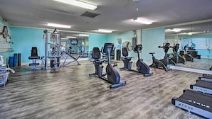 Ett gym med träningsutrustning, en vägg med speglar och ett trägolv.