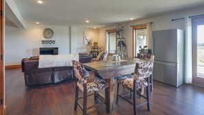A modern kitchen with a dining area, wooden flooring, a refrigerator, and a TV. - Rustic Missouri Vacation Rental w/ Hill Views! (Greenfield)