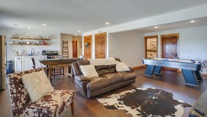 A spacious living area with a leather sofa, a pool table, and a cowhide rug. - Rustic Missouri Vacation Rental w/ Hill Views! (Greenfield)