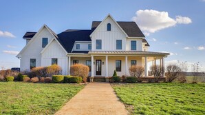 A large, two-story white house with a covered porch and a front walkway. - Rustic Missouri Vacation Rental w/ Hill Views! (Greenfield)