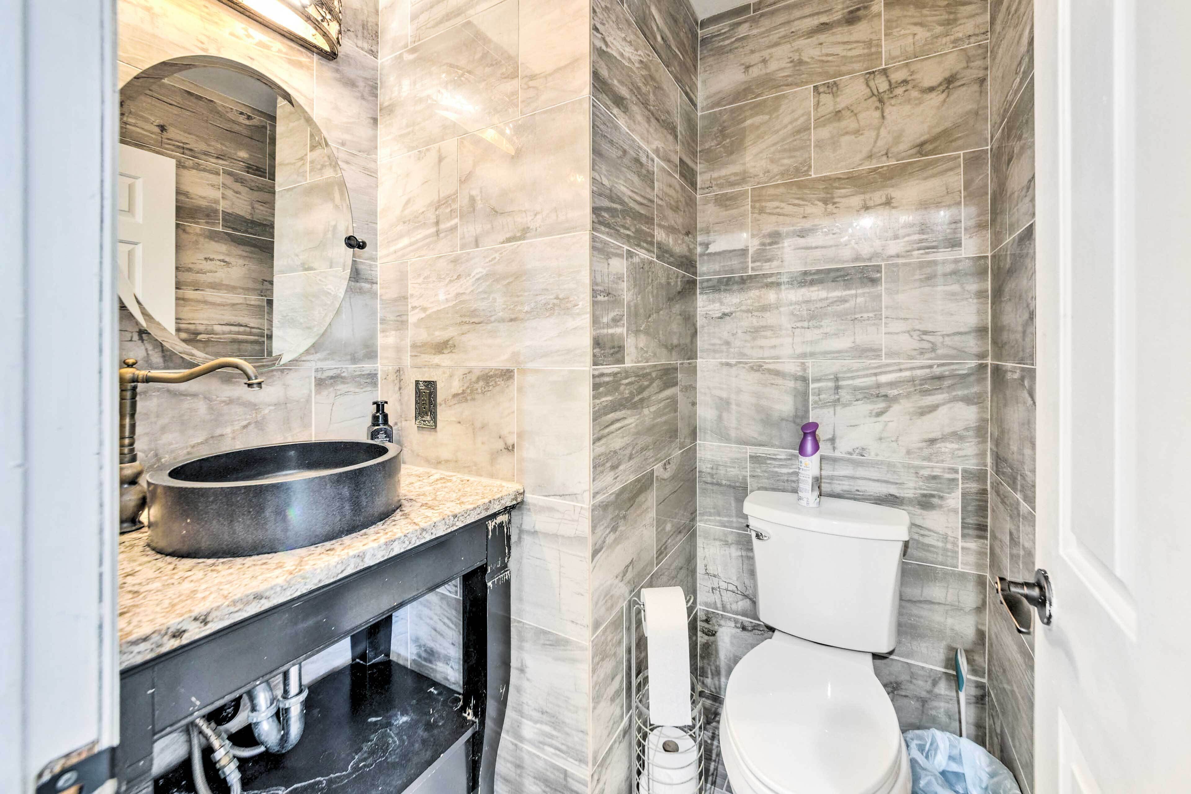 A bathroom with a marble sink, a toilet, and a mirror.