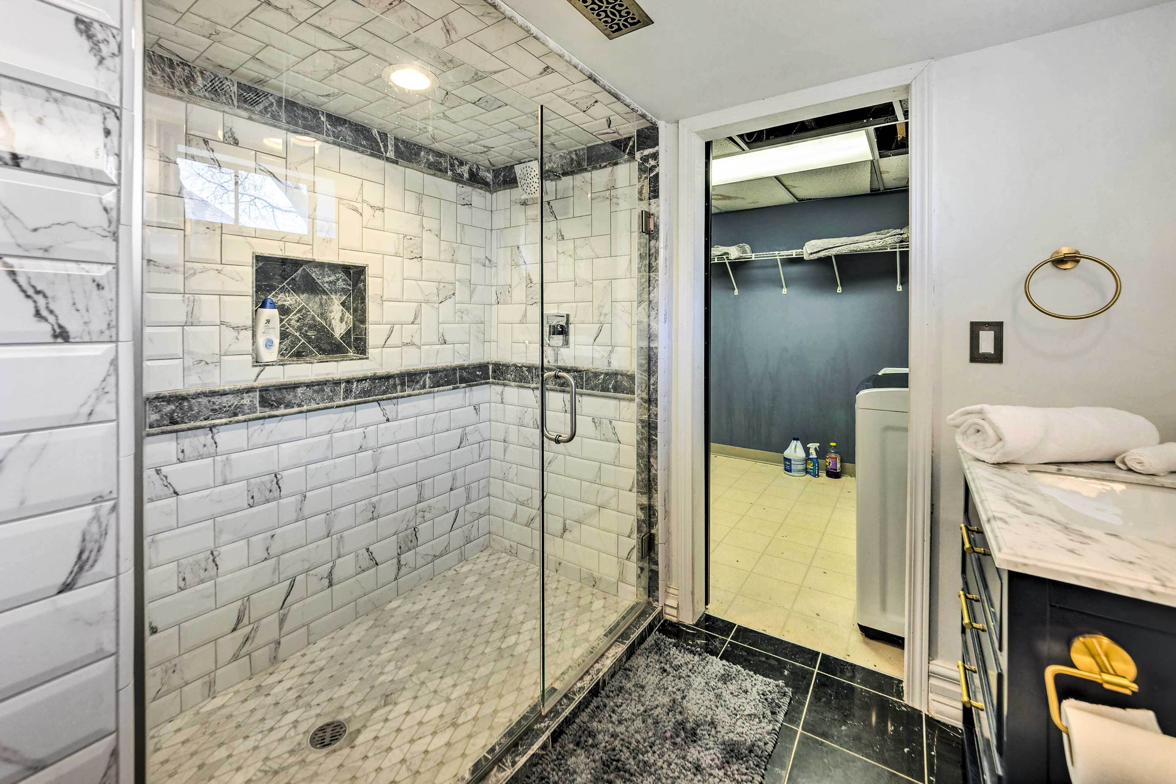 A modern bathroom with a glass-enclosed shower, marble tiles, and a black and white marble vanity.