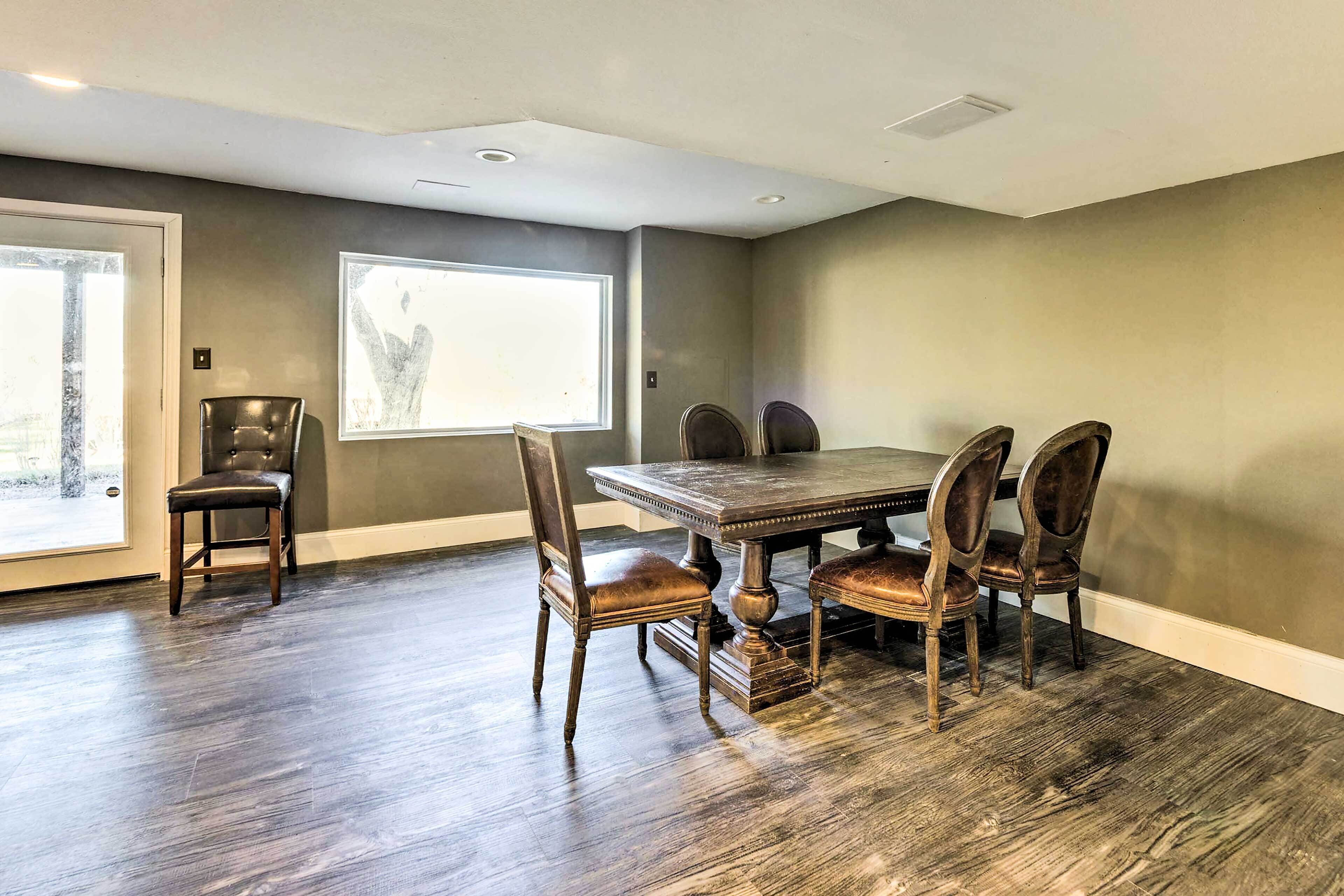 A dining area with a wooden table and chairs, a large window, and a door.