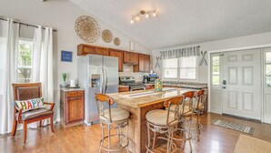 A kitchen with wooden cabinets, a central island with bar stools, a refrigerator, and a window with curtains. - Deck & Table Rock Lake View: Shell Knob Escape! (Shell Knob)