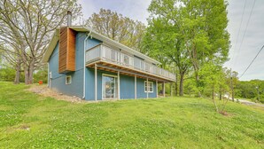 A two-story house with a balcony, surrounded by lush greenery and trees. - Deck & Table Rock Lake View: Shell Knob Escape! (Shell Knob)