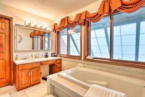 Bathroom features a bathtub, vanity area, and large mirror.