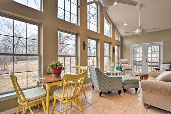 Enjoy a spacious living area with a dining table, comfortable seating, and a ceiling fan.