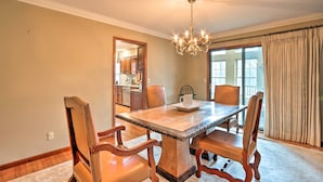 A dining area with a marble table, wooden chairs, a chandelier, and a view through a window with curtains. - Spacious Home w/ Pond ~ 13 Mi to Columbia! (Hallsville)