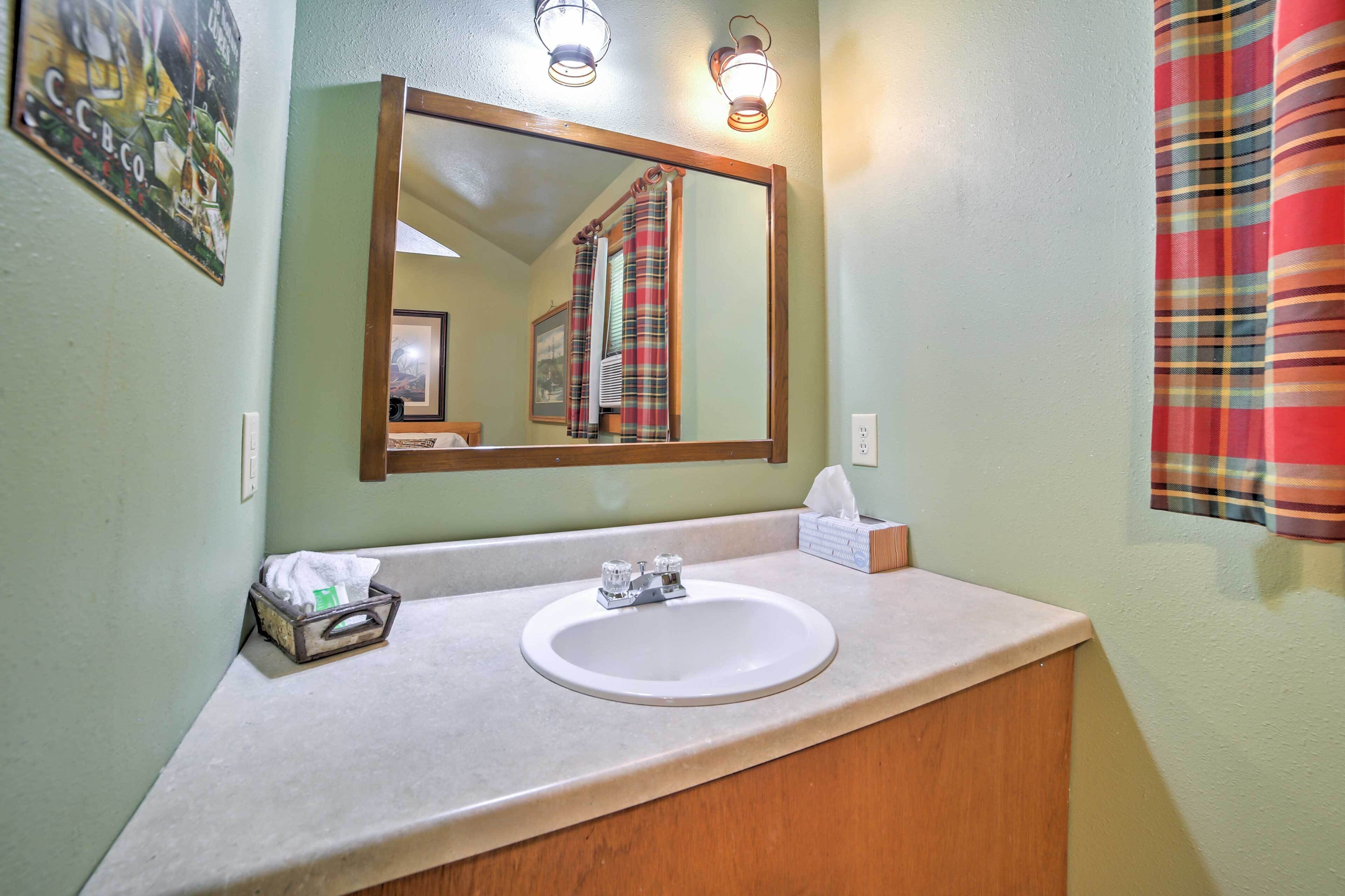 A bathroom with a white sink, a mirror, and a towel dispenser.