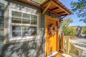 A wooden house with a yellow door, a welcome sign, and a wreath.