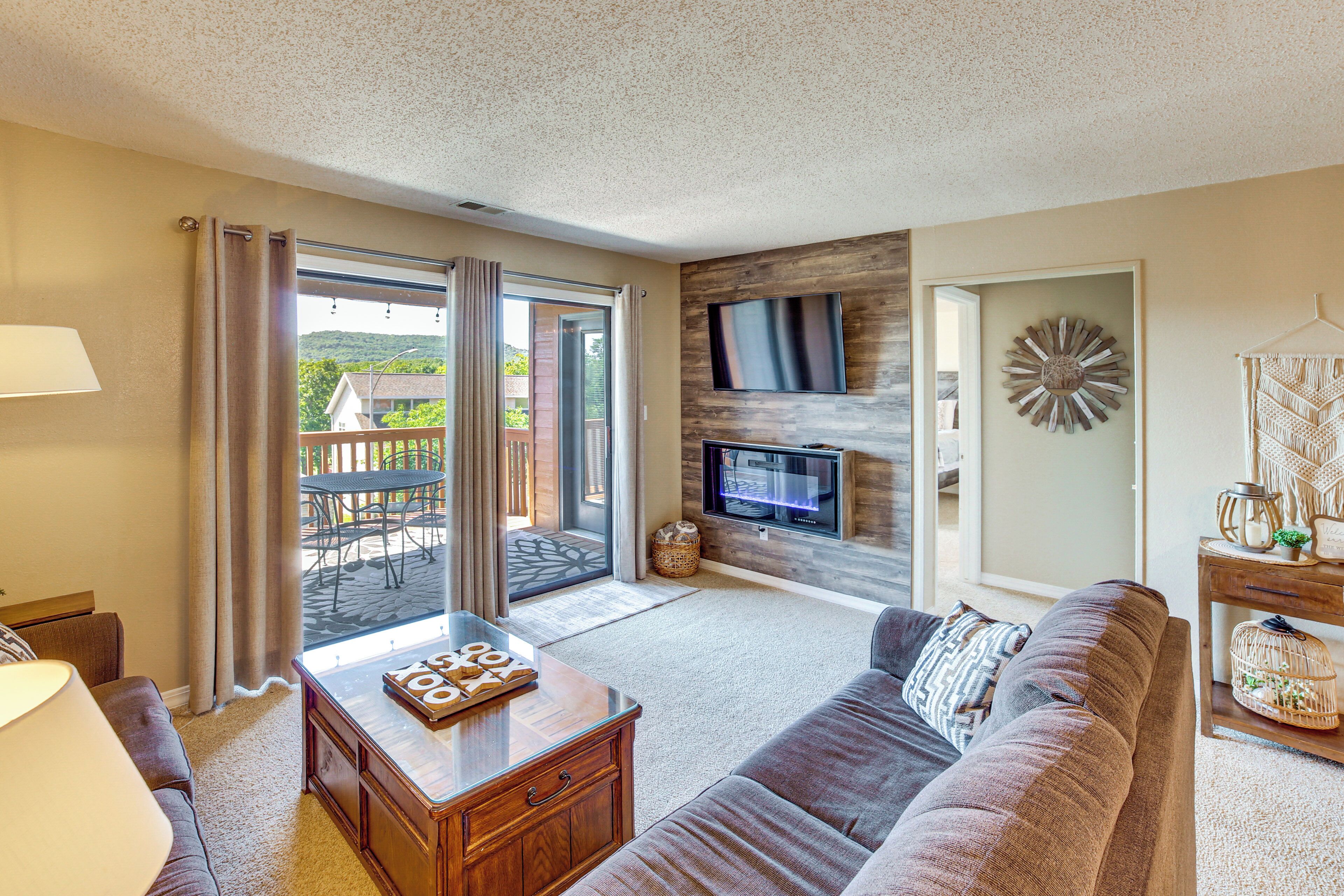 A living room with a sofa, a coffee table, a TV, and a view of the outdoors.