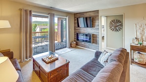A living room with a sofa, a coffee table, a TV, and a view of the outdoors. - Pool, Pickleball, Proximity to Popular Attractions (Branson)