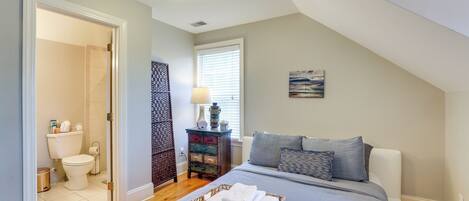 A bedroom with a bed, a bedside table, a lamp, and a window.