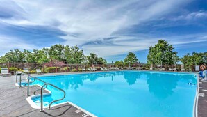 A swimming pool with clear blue water, surrounded by lounge chairs and a fenced area with trees. - Branson Resort Condo w/ Scenic Patio & Pool Access (Branson)