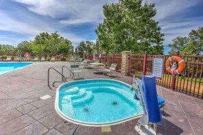A swimming pool with lounge chairs and a lifebuoy, surrounded by a fence and trees.