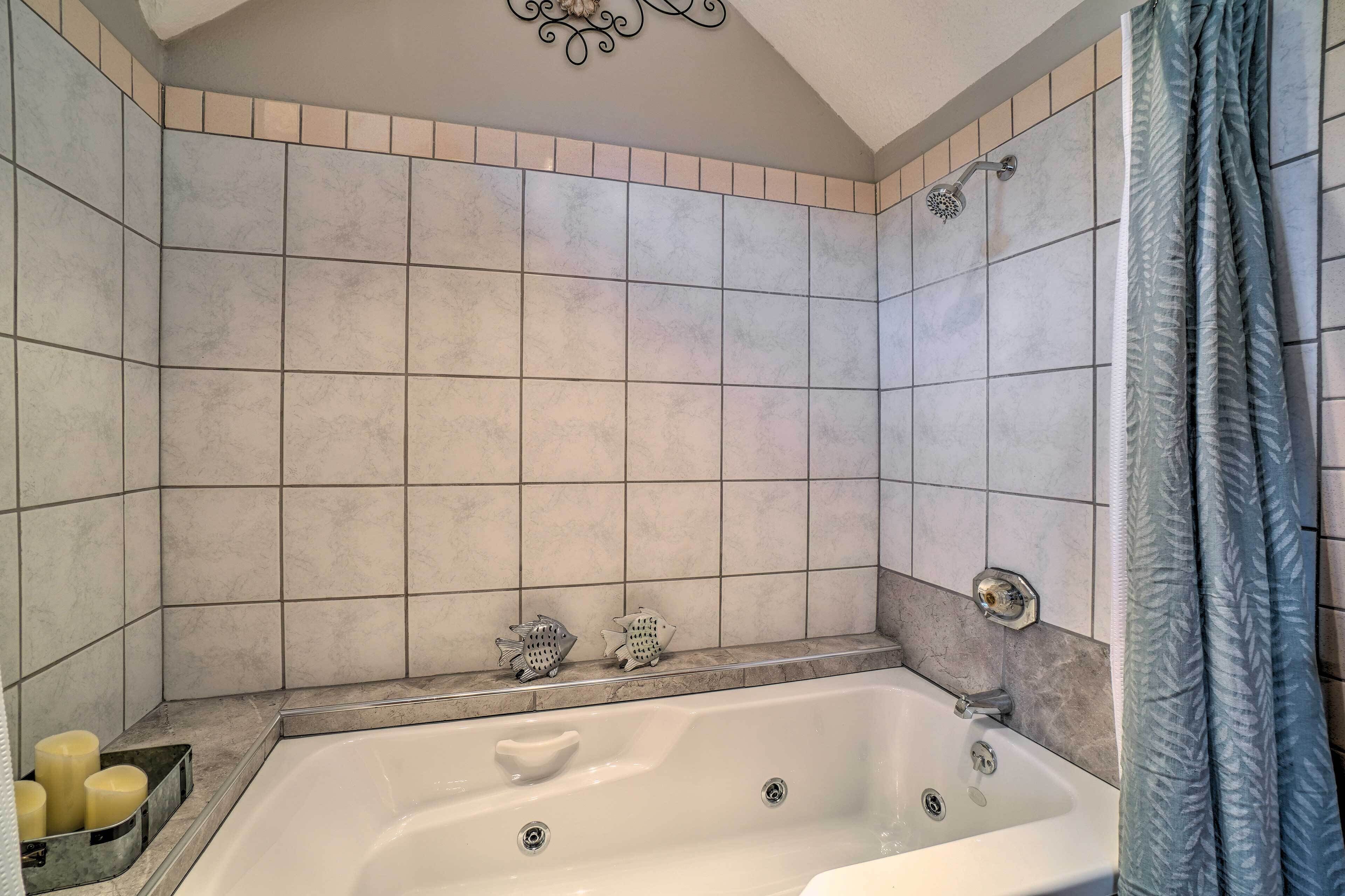 A bathroom with a bathtub, tiled walls, a showerhead, and a curtain.
