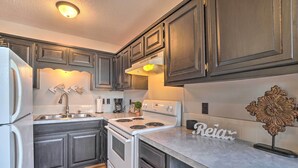 A kitchen with dark wooden cabinets, a white stove, and a countertop with a decorative piece and a sign that reads "Reiar". - Shell Knob Guest House w/ Lake View, Fire Pit (Shell Knob)