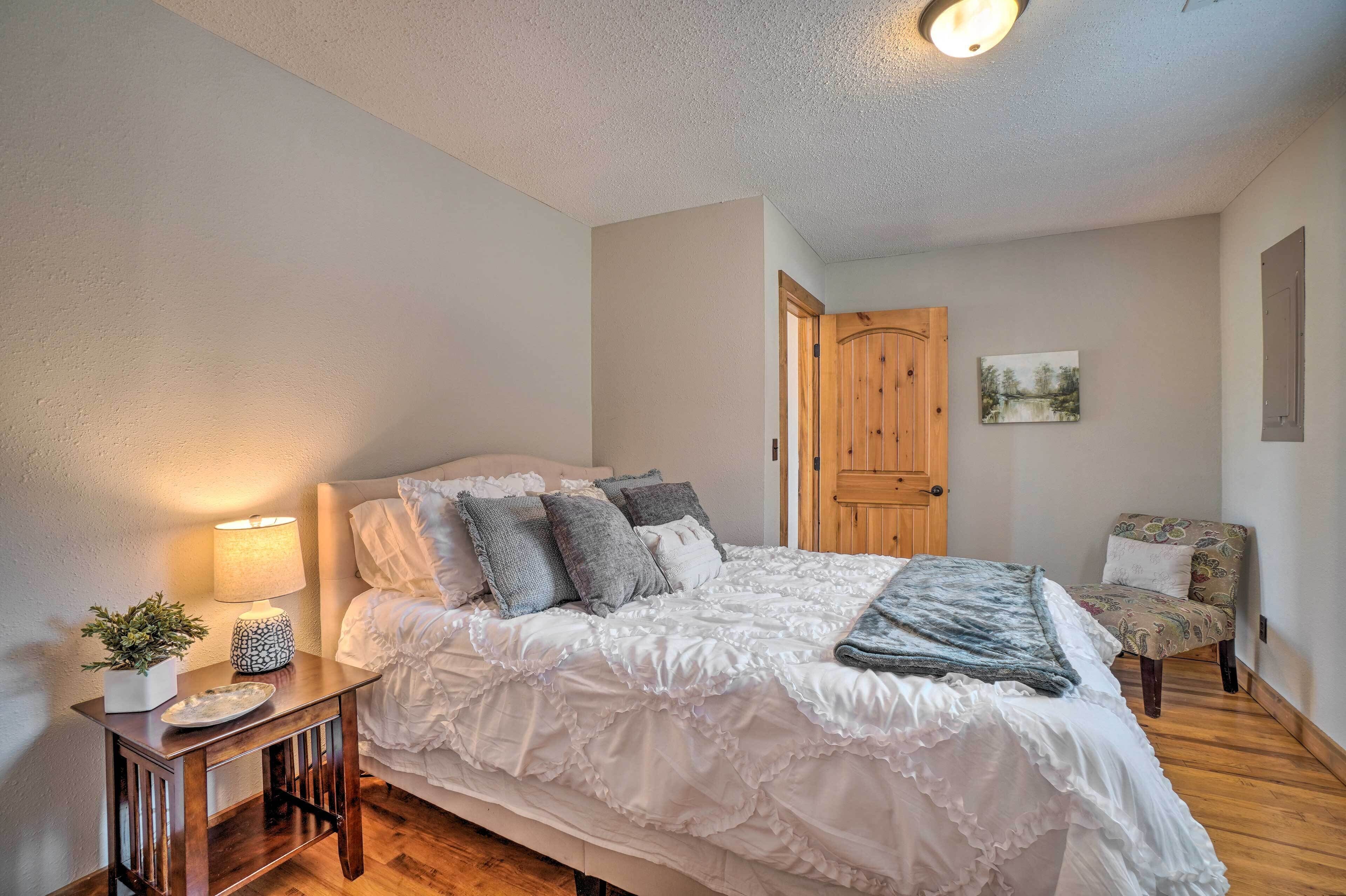 Une chambre à coucher avec un lit, une table de chevet, une lampe, une chaise et une porte.
