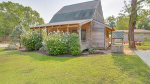 A log cabin with a porch, surrounded by well-maintained grass and bushes. - Rustic Hollister Cabin - 5 Mi to Downtown Branson (Hollister)