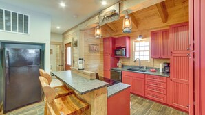 A kitchen with wooden cabinets, a refrigerator, a microwave, and a sink. - Rustic Hollister Cabin - 5 Mi to Downtown Branson (Hollister)