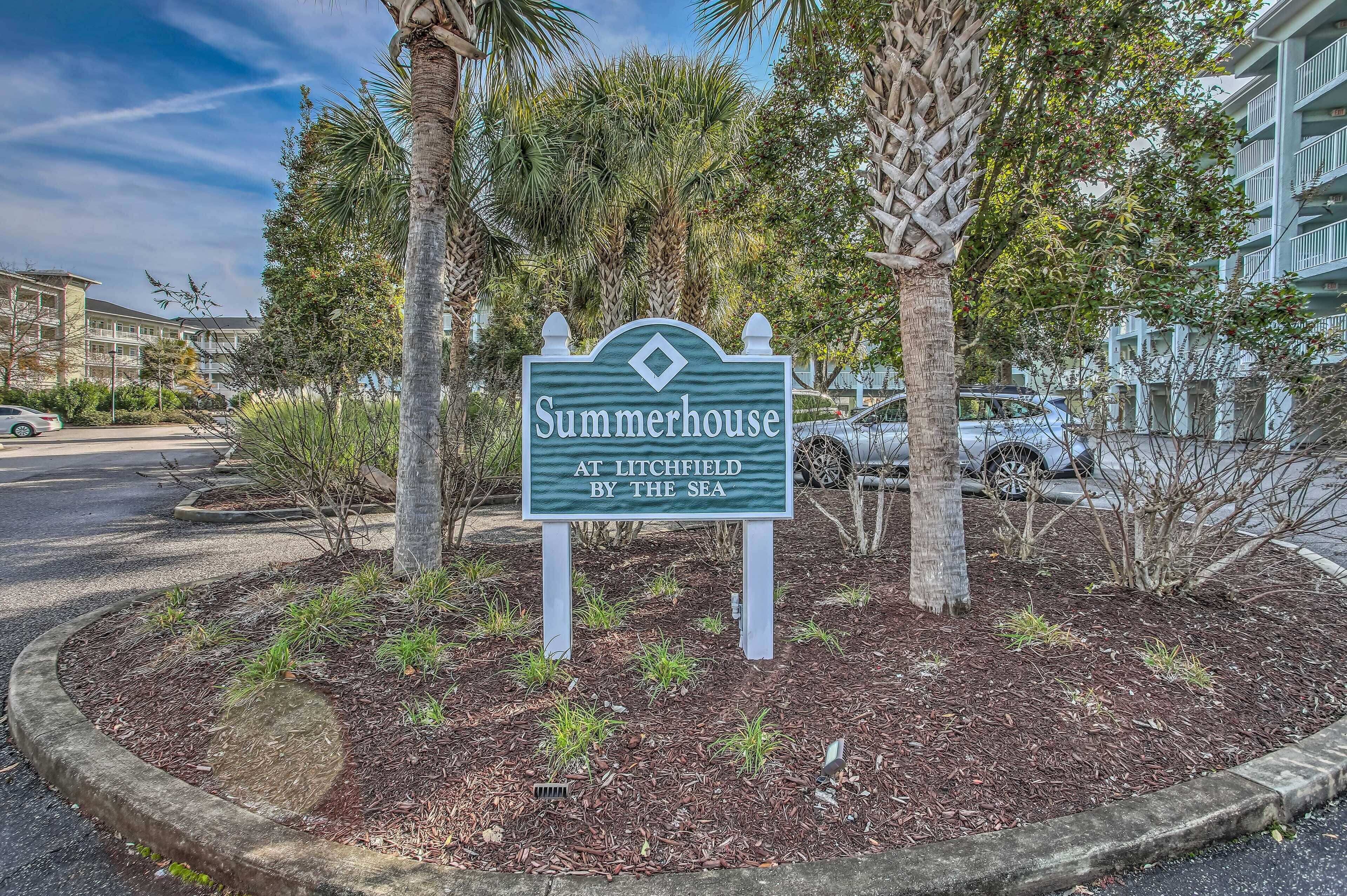 A sign for 'Summerhouse at Litchfield by the Sea' with a landscaped area featuring palm trees and shrubs.