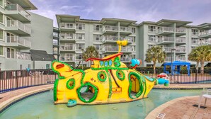 A colorful submarine play structure in a pool area with a backdrop of a multi-story hotel building. - Summerhouse Villas Condo: Private Resort Beach! (Pawleys Island)