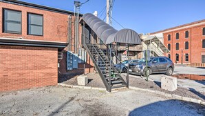 A parking garage entrance with a covered stairway leading to a building with a brick facade and a car parked nearby. - Sleek, Modern Loft in Downtown Springfield! (Springfield)