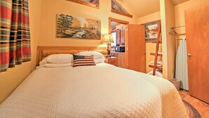 A bedroom with a large bed, a painting on the wall, a wooden ceiling, and a door leading to a bathroom. - Near Shopping & Museums: Quiet Branson Cabin (Branson)