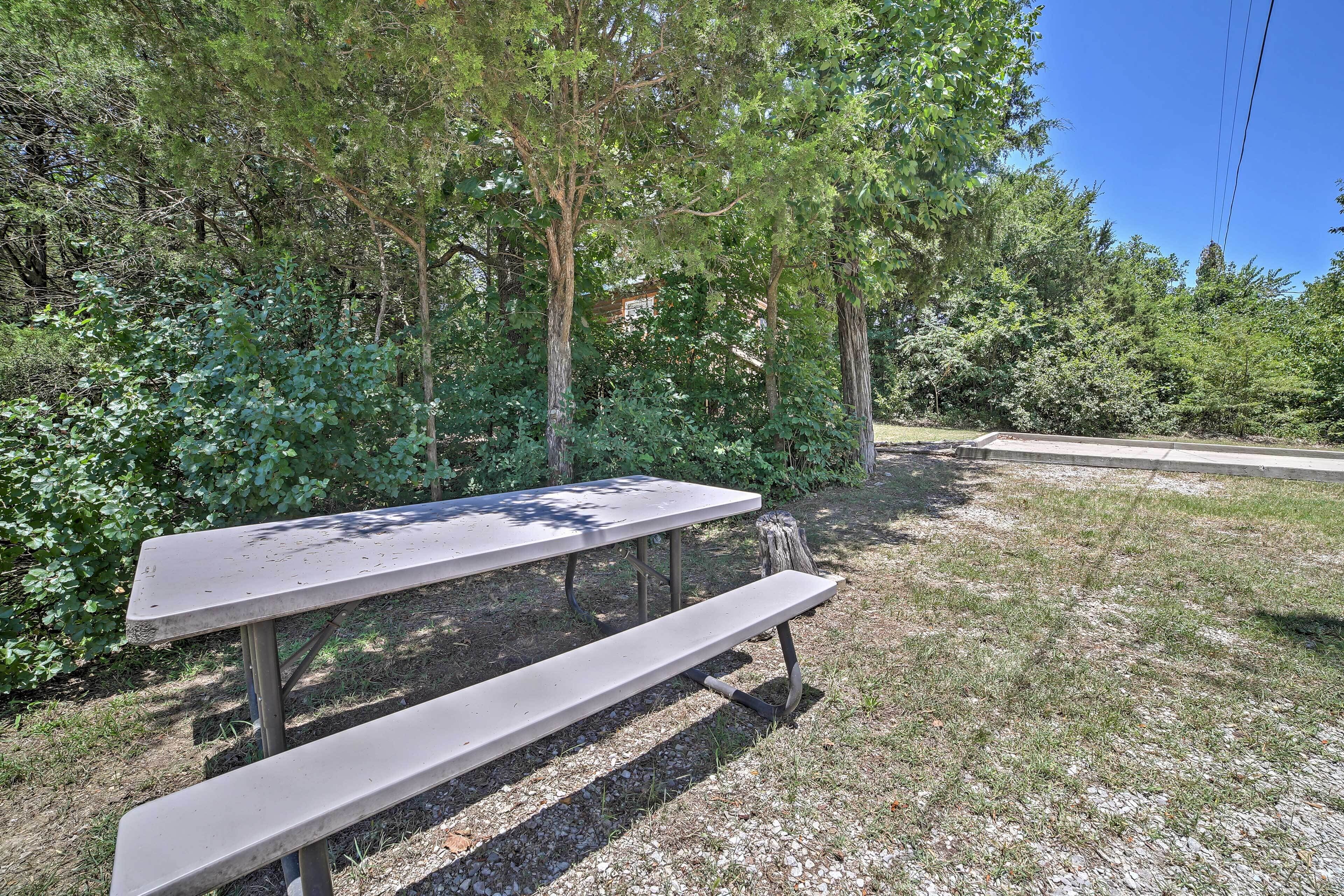 A picnic table in a wooded area with trees and a clear sky.