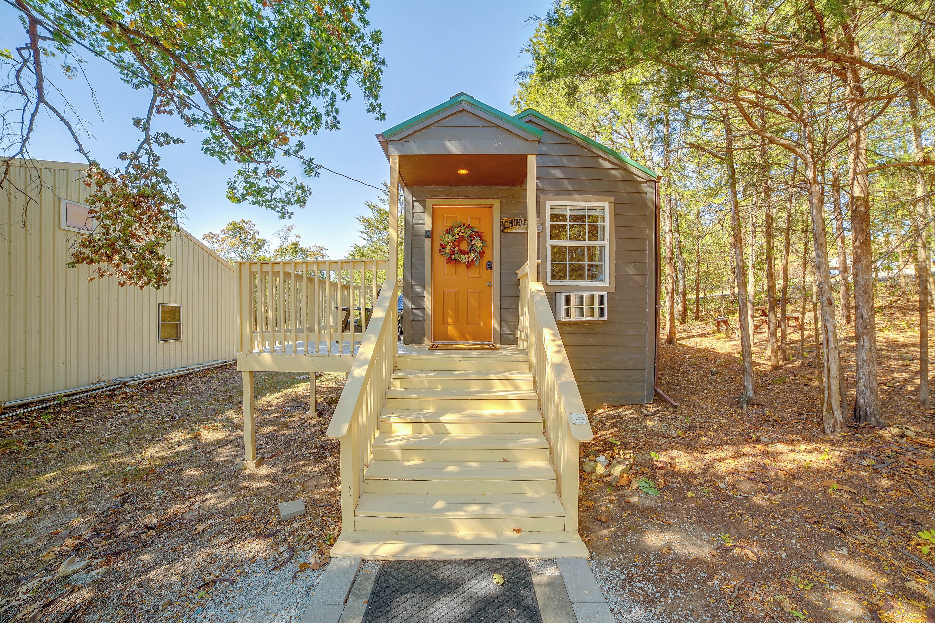 A small wooden cabin with a porch and a door, surrounded by trees.