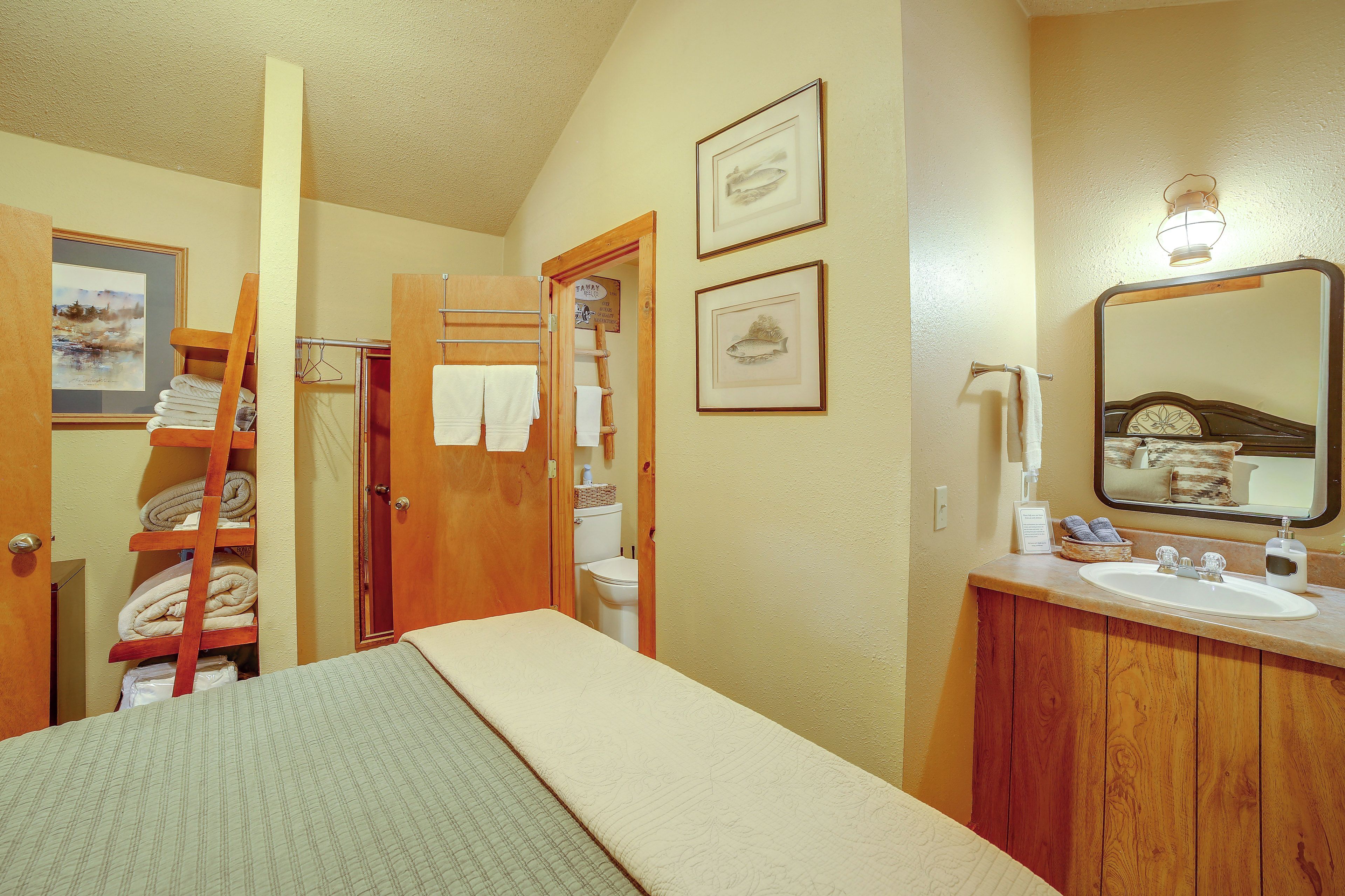 Una habitación con una cama, una escalera de madera, un inodoro y un lavabo con espejo.