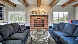 A cozy living room with a brick fireplace, two sofas, and a coffee table. - Remodeled Historic Farmhouse ~ 20 Mi to KC! (Liberty)