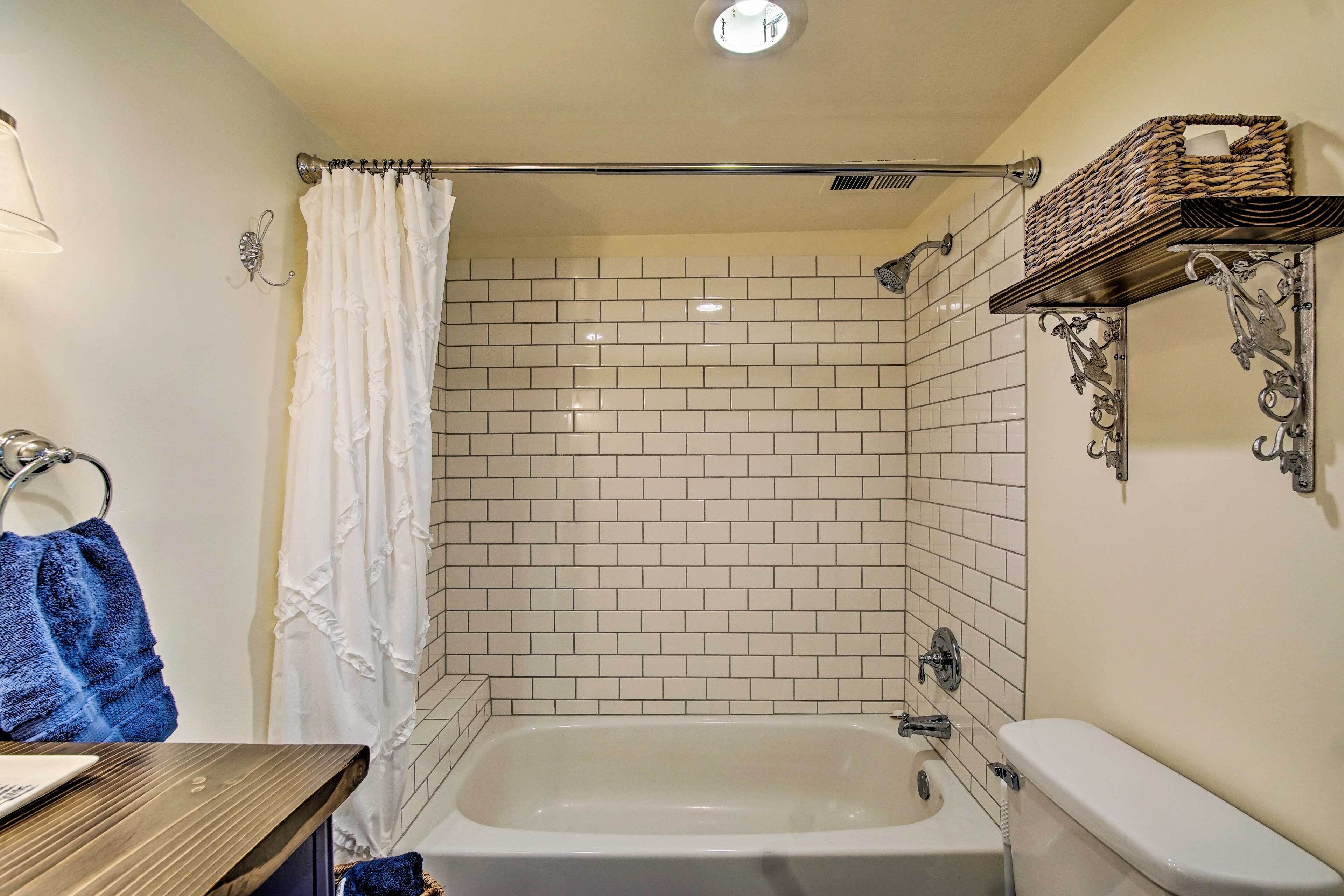 Un baño con bañera, inodoro, cortina de ducha y un perchero con una toalla azul.