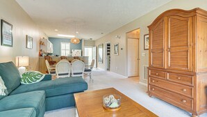 A spacious living room with a sofa, coffee table, and a wooden cabinet. - Sunny Coastal Condo ~ 1 Mi to N Myrtle Beach! (North Myrtle Beach)