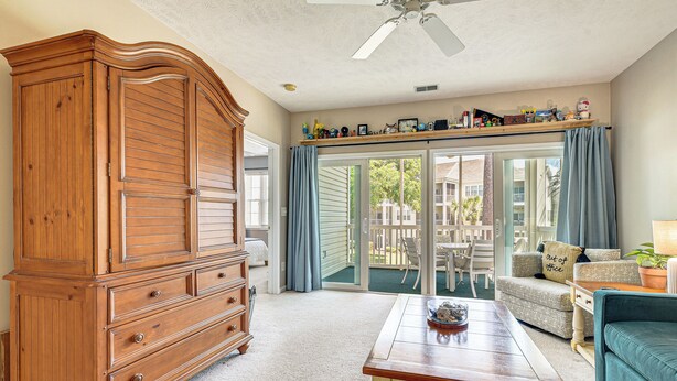 A spacious living room with a wooden cabinet, a coffee table, and a sofa. - Sunny Coastal Condo ~ 1 Mi to N Myrtle Beach! (North Myrtle Beach)