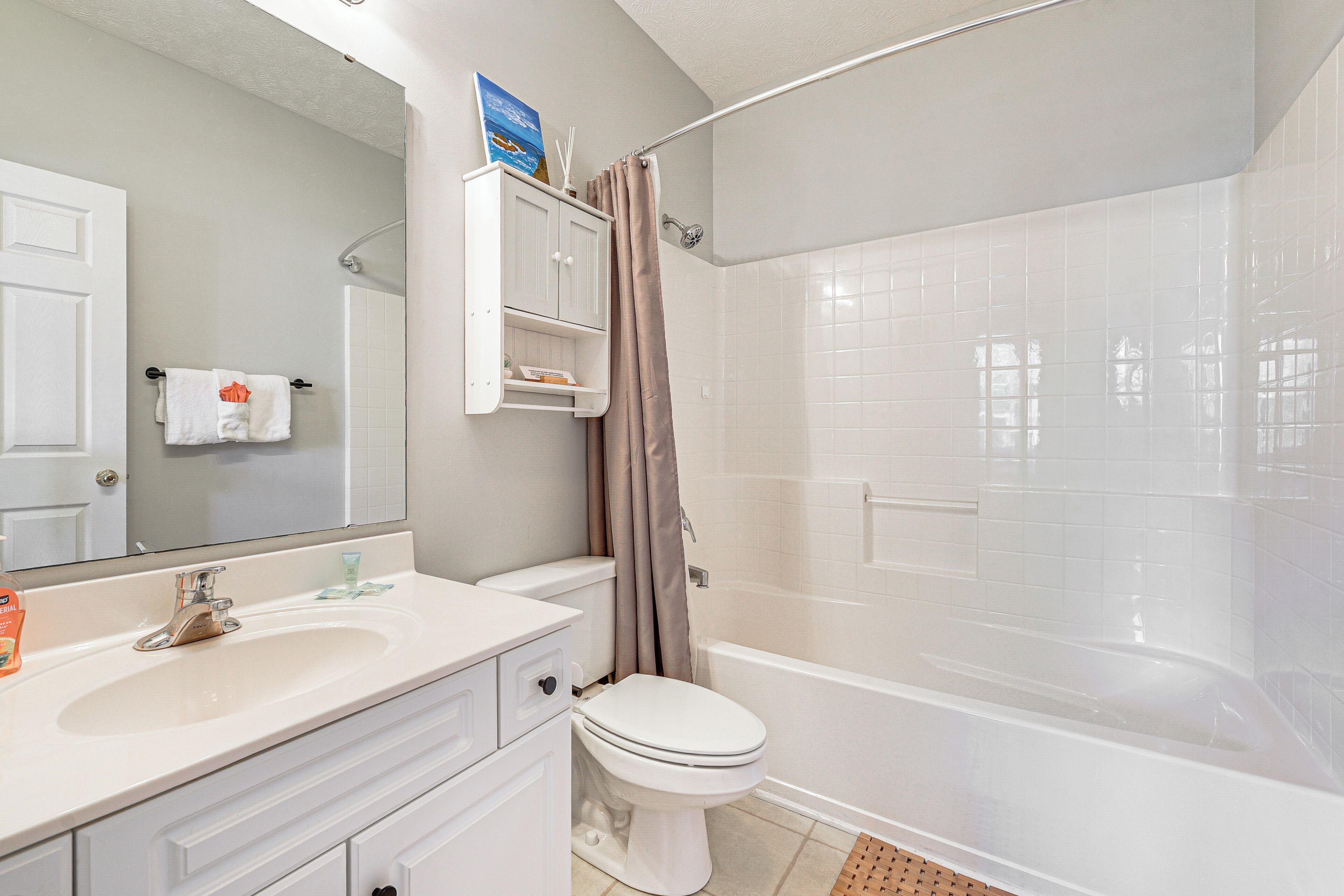 A bathroom with a toilet, sink, mirror, shower curtain, and a bathtub.