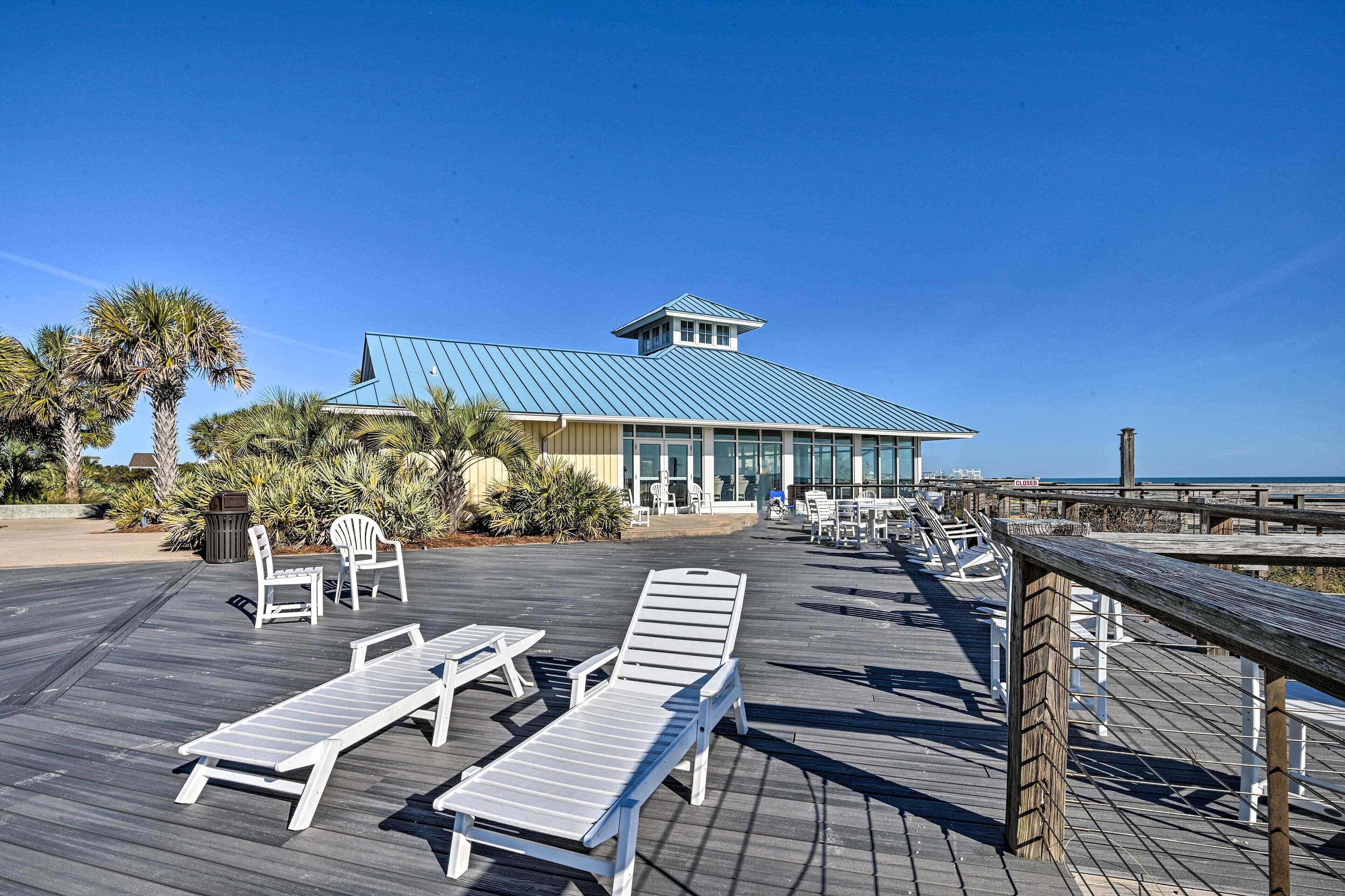 A wooden deck with lounge chairs and a building with a blue roof.