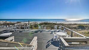 Eine Holzterrasse mit Sitzgelegenheit und Blick auf den Strand.