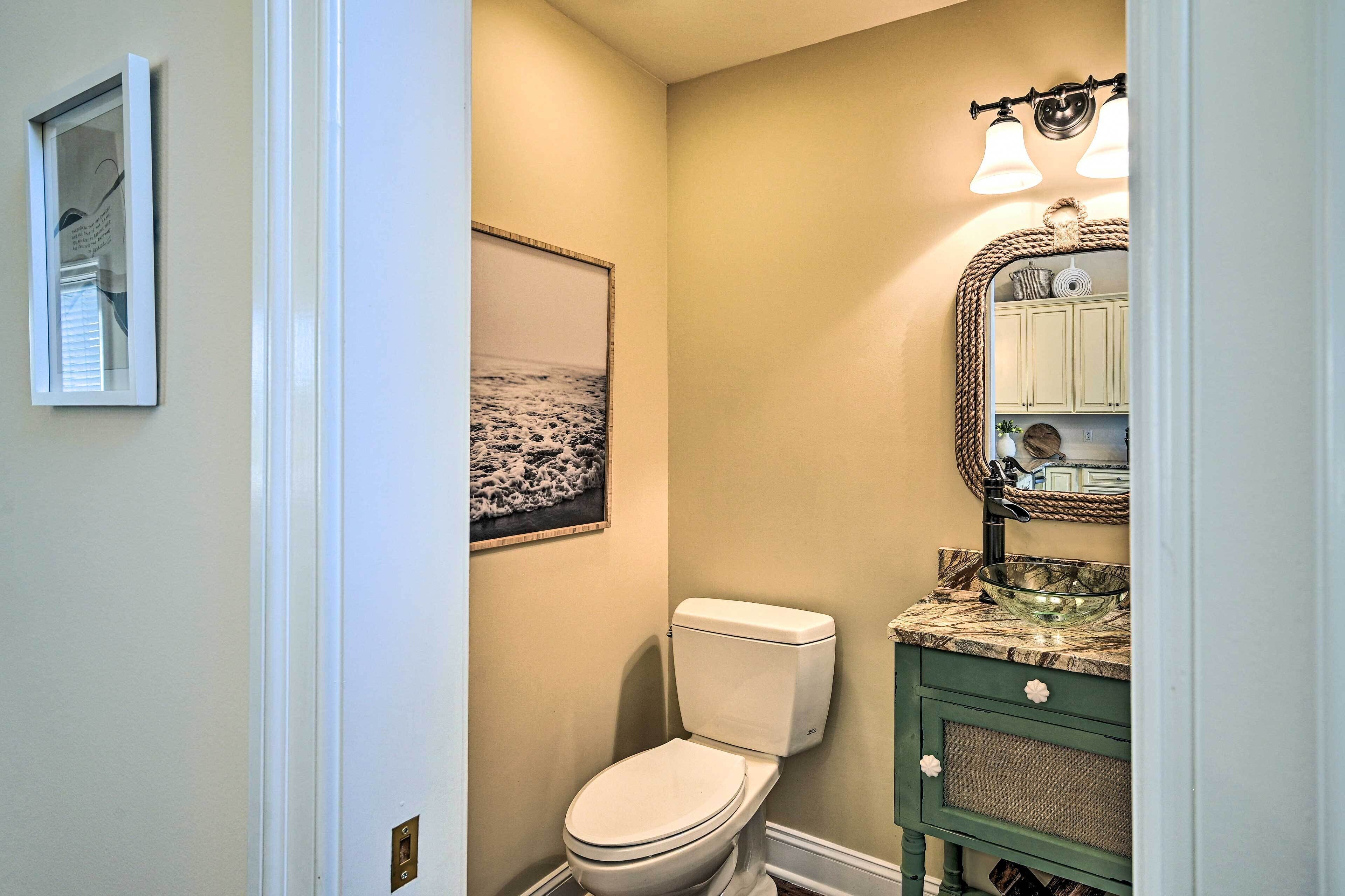 Une salle de bain avec des toilettes, un lavabo avec un miroir et un tableau encadré au mur.