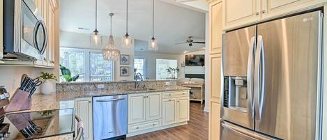 A modern kitchen with stainless steel appliances, granite countertops, and pendant lighting.