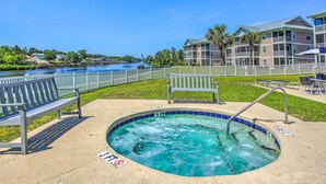 A pool area with a hot tub, benches, and a view of a river and buildings. - Sunny N Myrtle Condo w/ Pool < 2 Mi to Beach! (North Myrtle Beach)