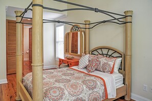 A four-poster canopy bed with a patterned bedspread, a wooden headboard, and a bedside table with a mirror and basket. - Spacious Lakefront Retreat w/ Fishing Dock & Deck! (Murrells Inlet)
