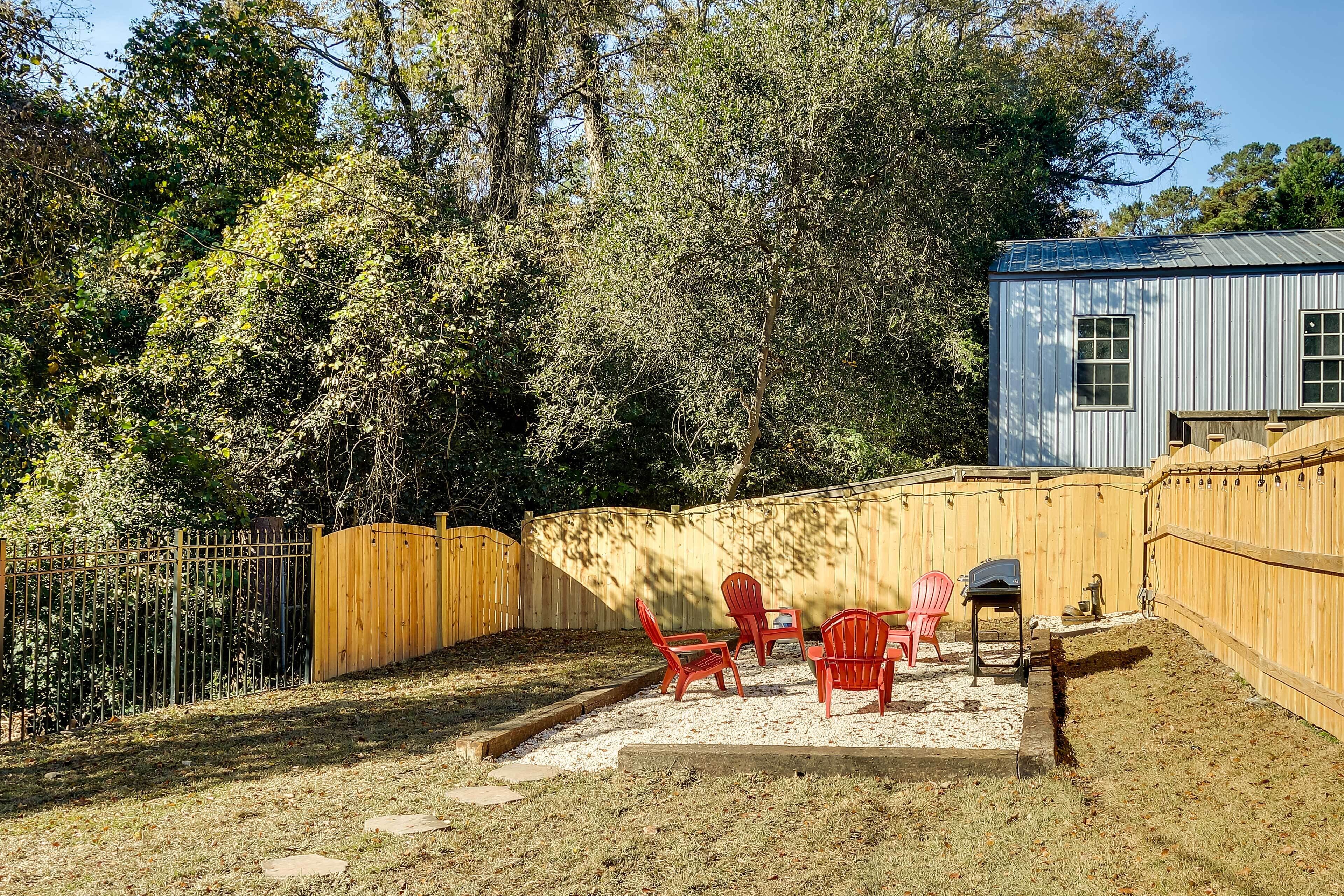 A backyard with a wooden fence, red chairs, and a small table.